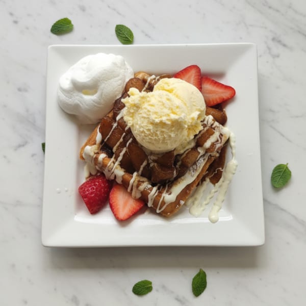 Breakfast Bunny's waffle with ice cream, whipped cream, strawberries, and apple pieces.